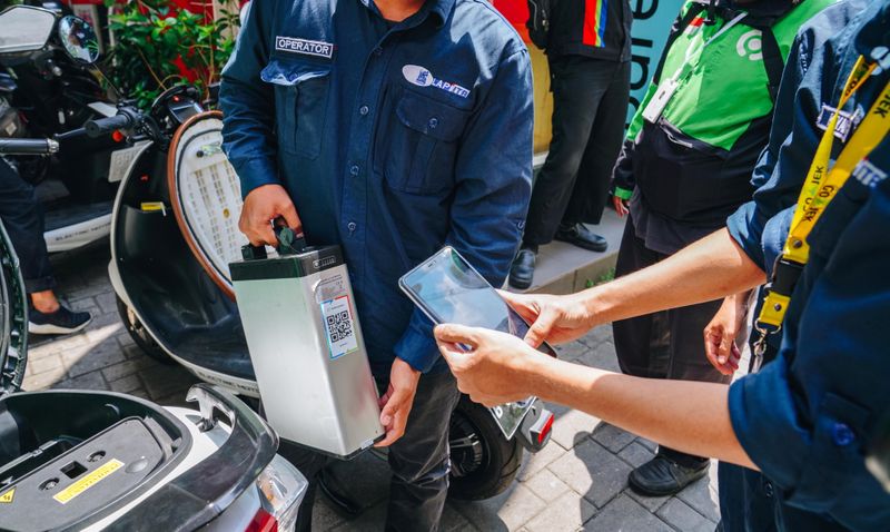 Operators scan a Gojek taxi rider’s battery barcode to charge