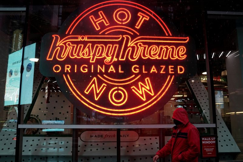 A man walks past a Krispy Kreme “Hot Now” neon