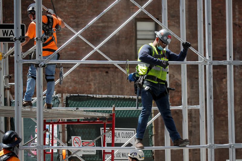 Construction workers assemble a scaffold at a job site, as