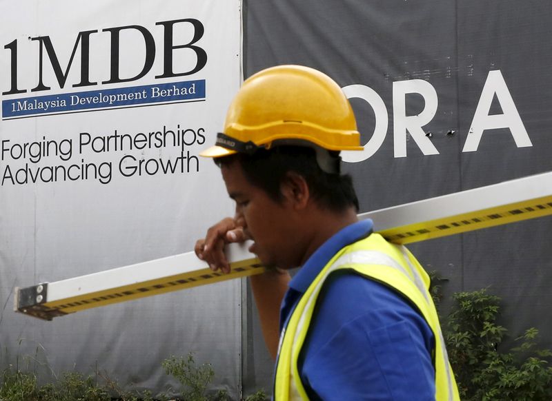 A construction worker walks past a 1Malaysia Development Berhad (1MDB)