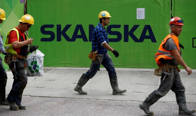 FILE PHOTO: Workers walk past a Skanska logo seen on