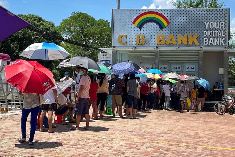 People line up outside a bank to withdraw cash, in