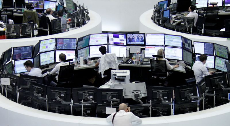 FILE PHOTO: Traders work at their desks in front of