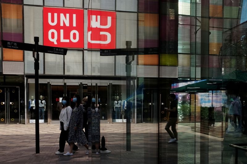 Women walk past a store of Fast Retailing’s fashion chain