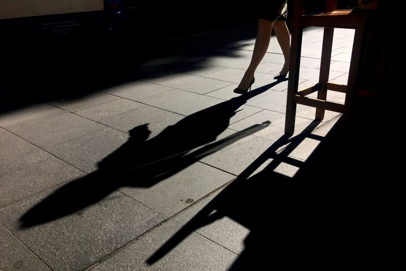FILE PHOTO: A woman casts a shadow as she walks