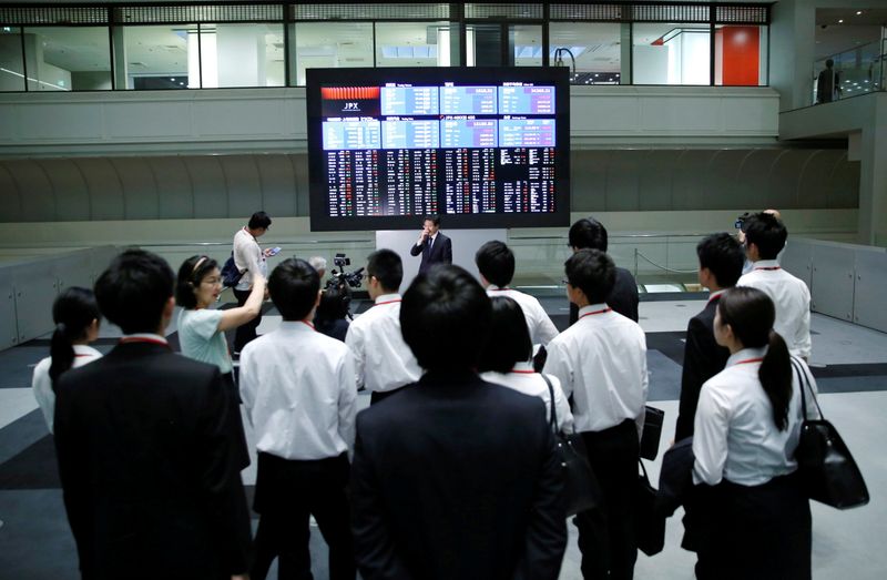 FILE PHOTO: Visitors look at an electronic stock quotation board