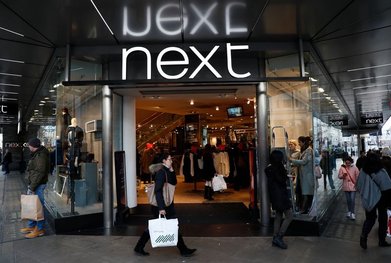 Pedestrians walk past a Next store in central London