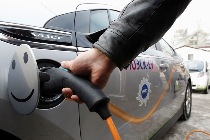 FILE PHOTO: A man charges an electric car during a