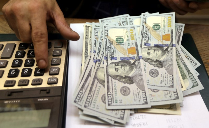FILE PHOTO: An employee counts U.S. dollar bills at a