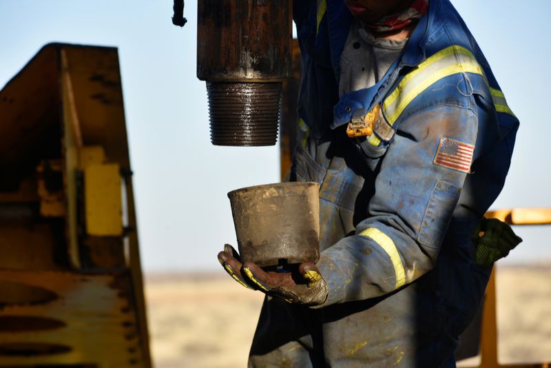 An oil worker removes a thread cap from a piece