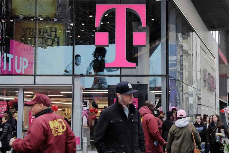 Pedestrians walk past a T-Mobile store in New York