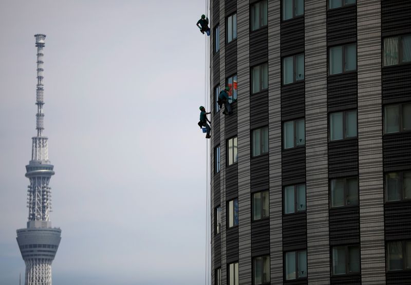 Workers clean the windows of a hotel with Tokyo Skytree,