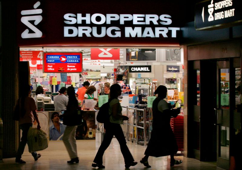 FILE PHOTO: People walk past a Shoppers Drug Mart store