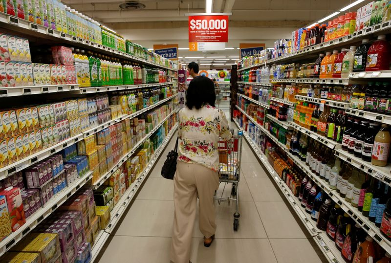 A woman pushes a shopping cart at a supermarket in