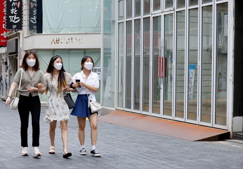 FILE PHOTO: Women wearing masks walk in a shopping district