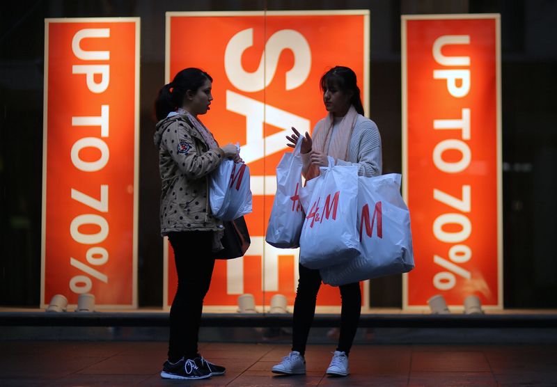 Shoppers carry shopping bags containing purchased goods outside a retail