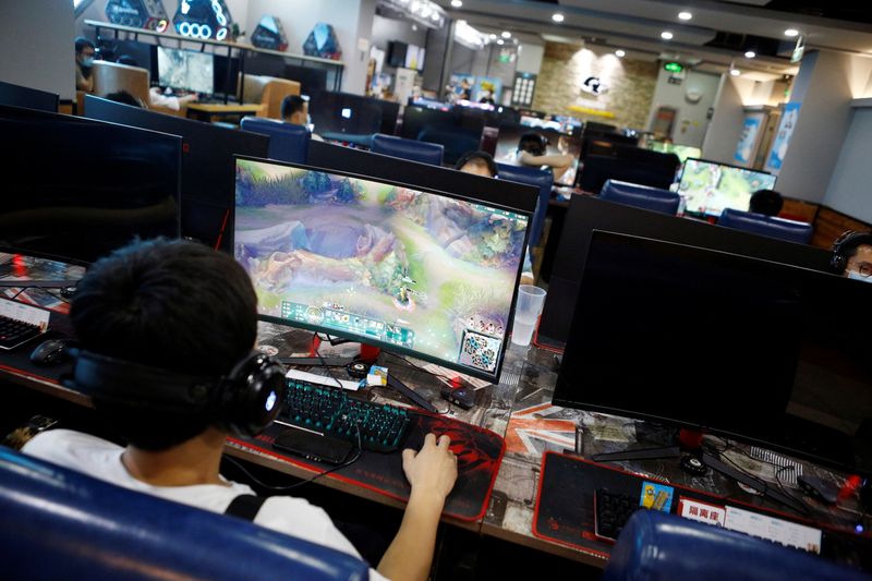 People play online games on computers at an internet cafe