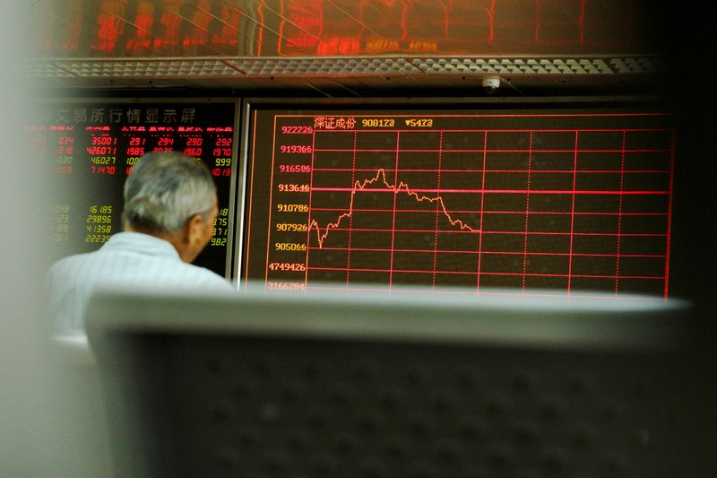 A man sits in front of a board showing market