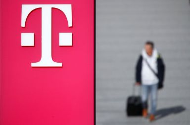 A man walks past the logo of Deutsche Telekom AG