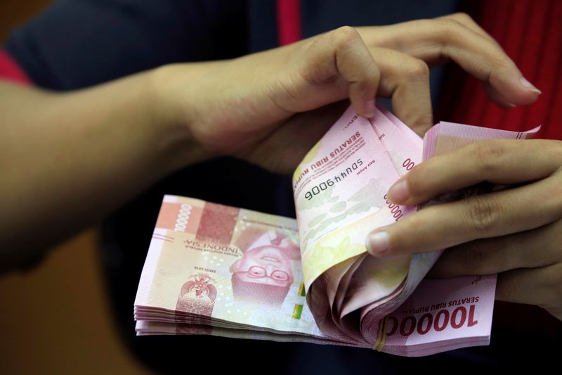 An employee counts Indonesian rupiah banknotes at a currency exchange
