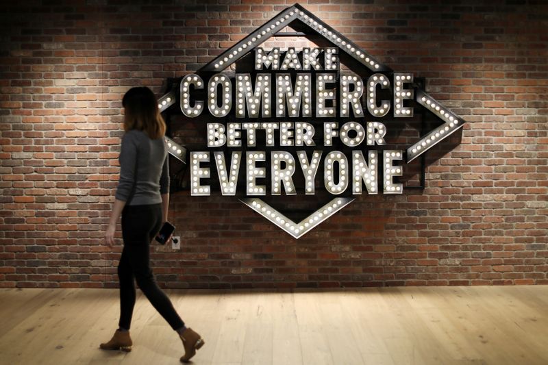 FILE PHOTO: An employee walks past a sign at Shopify’s