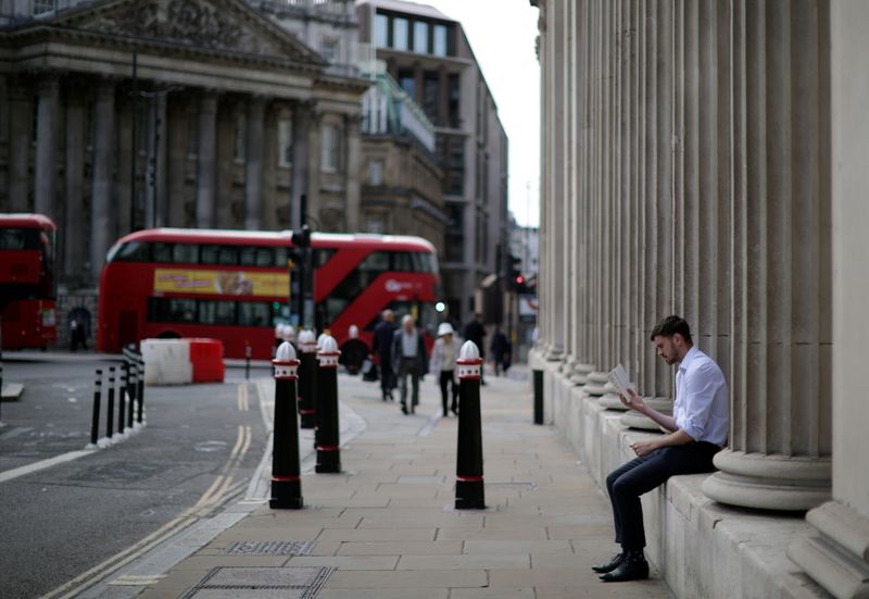 A person reads a book outside the Bank of England