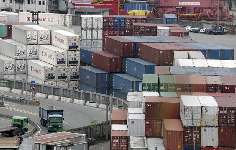 FILE PHOTO: Trucks drive near containers at Keelung port, northern