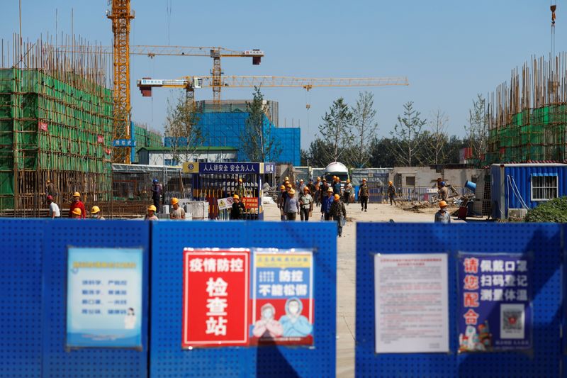 Workers walk inside the construction site of a project developed