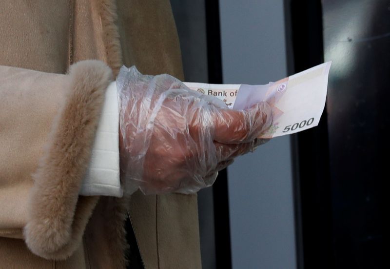FILE PHOTO: A woman wearing a plastic glove holds money