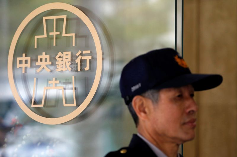 Police officer stands beside the Taiwanese Central Bank logo in