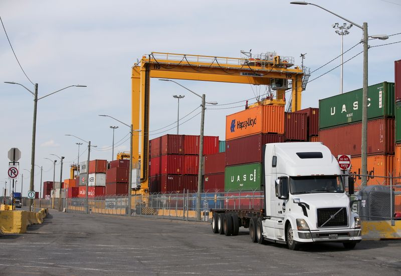 FILE PHOTO: A truck moves past stacked shipping containers at