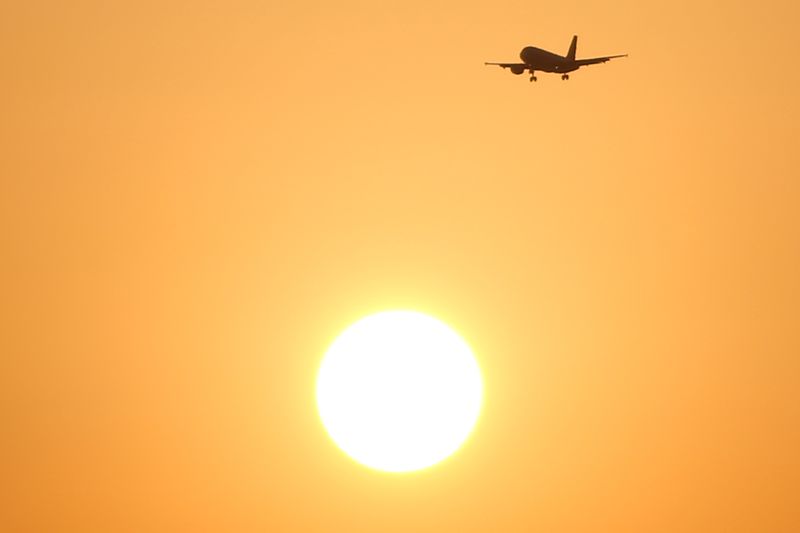 A passenger aircraft flies past the sun at sunset during