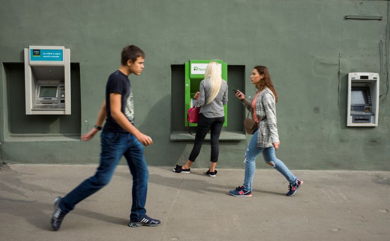 A woman uses an ATM machine as people walk past