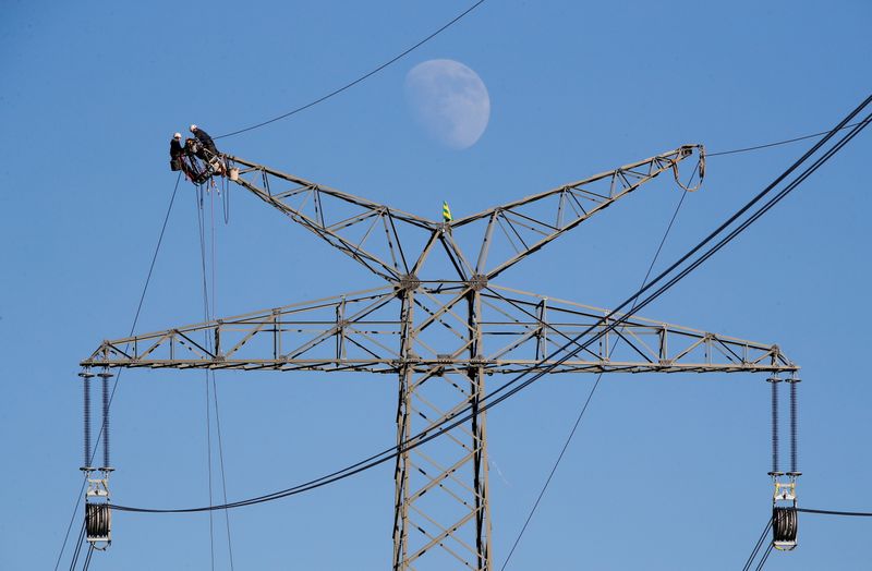 FILE PHOTO: The moon rises as electricians work atop a