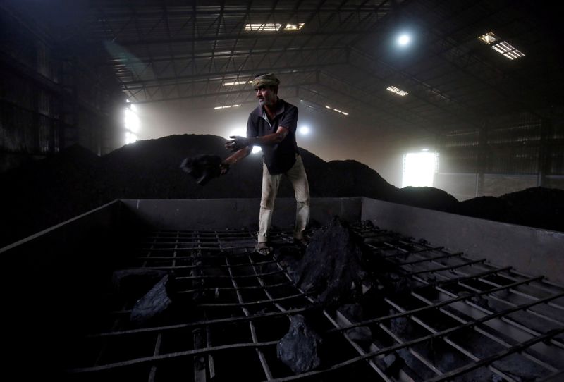 FILE PHOTO: A worker shovels coal in a supply truck