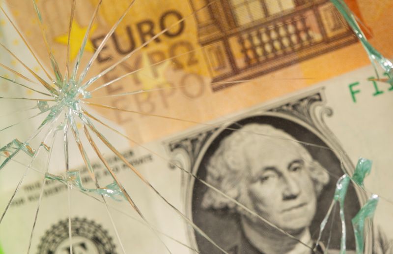 U.S. dollar and euro banknotes are seen through broken glass