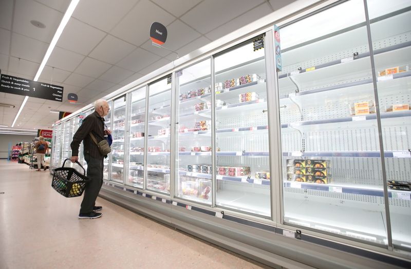A shopper looks at produce and empty shelves of the