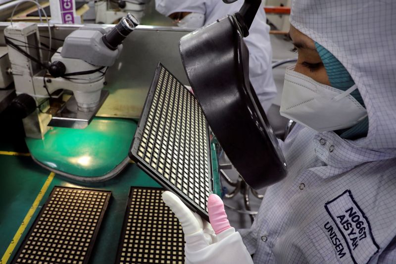 A worker inspects chips at the semiconductor packaging firm Unisem