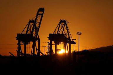 FILE PHOTO: The sun sets behind container cranes at the