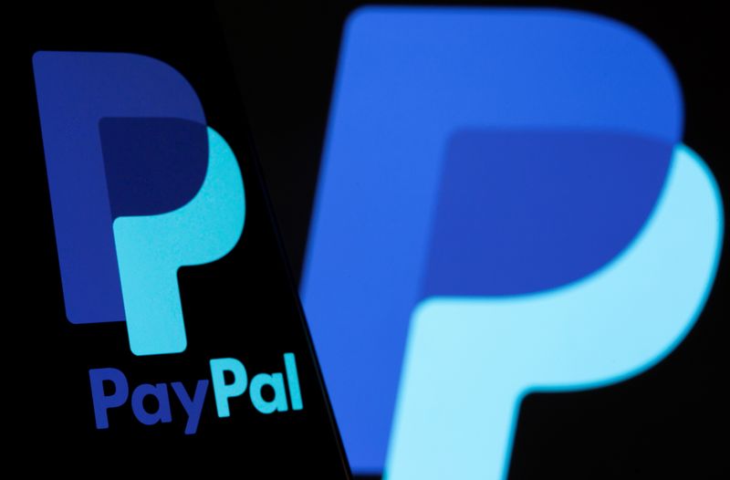 The PayPal logo is seen on a smartphone in front