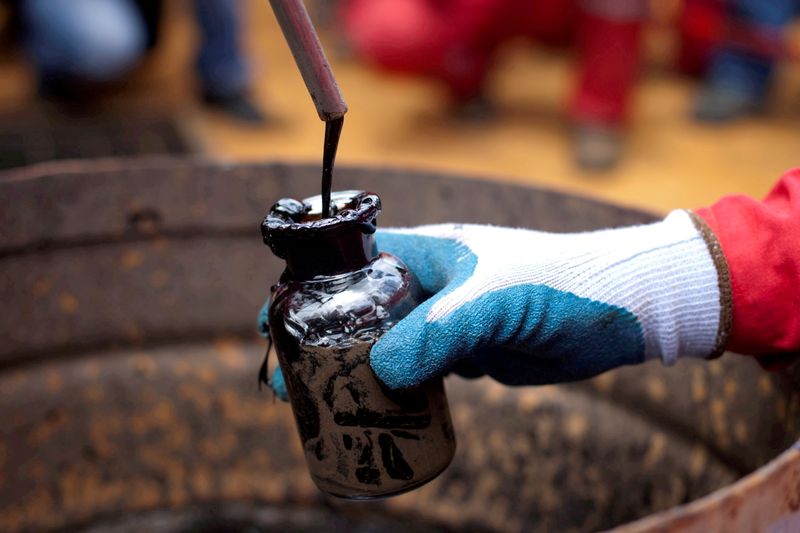 FILE PHOTO: A worker collects a crude oil sample at