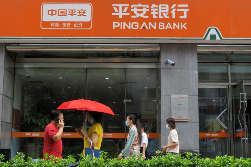 People walk past a branch of Ping An Bank, a