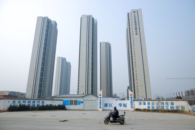 A man rides a scooter past apartment highrises that are