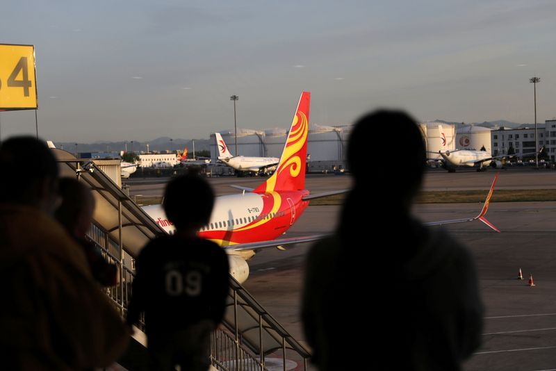 Travellers are seen in front of an airplane of Hainan