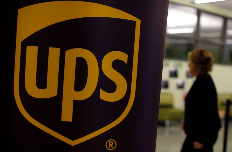 Woman walks past a sign bearing the UPS logo at