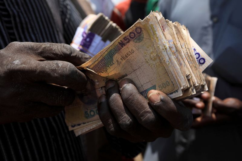 Man carries Nigerian naira banknotes at a livestock market in