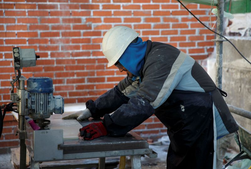 FILE PHOTO: A worker cuts tiles at a construction site