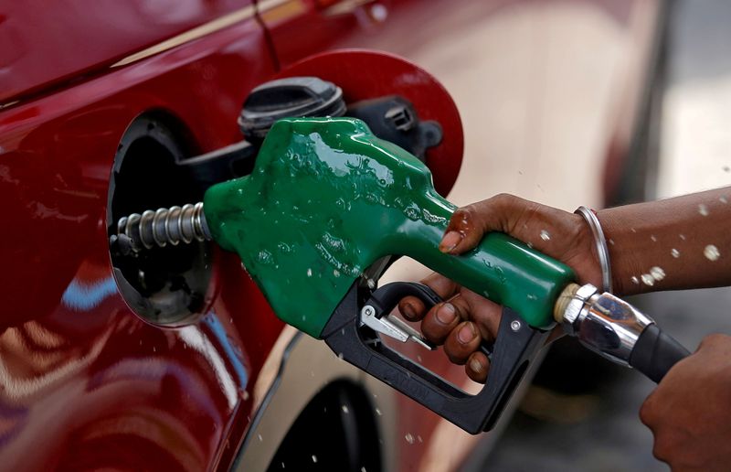 FILE PHOTO: A worker holds a nozzle to pump petrol