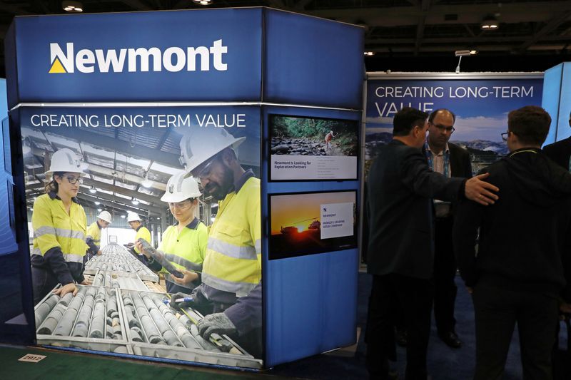 Visitors speak with a representative at the Newmont Corp booth