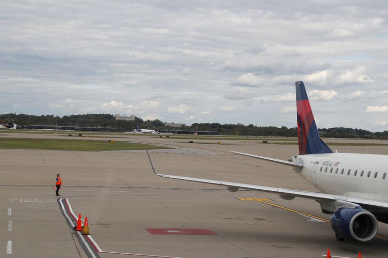 An airport worker stands on a tarmac next to a